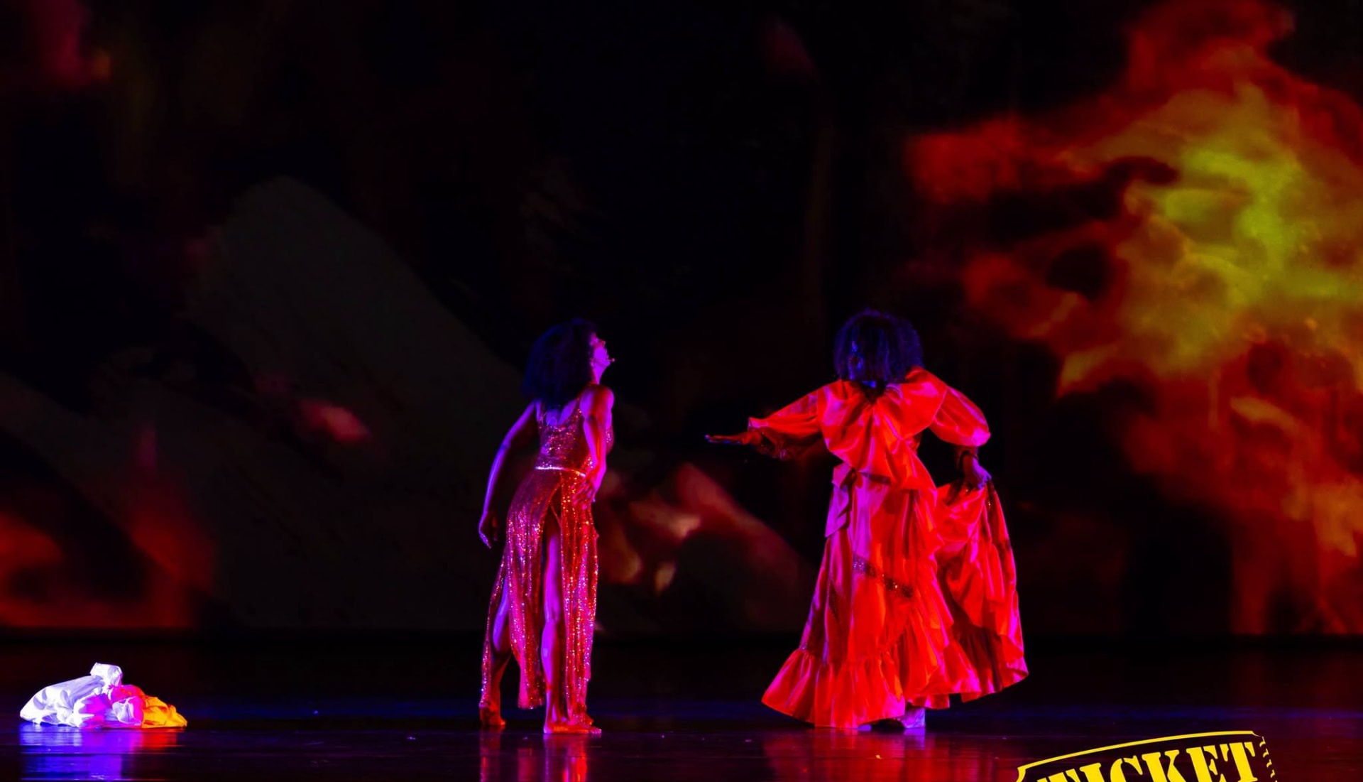 Two performers in red before a wall of fire