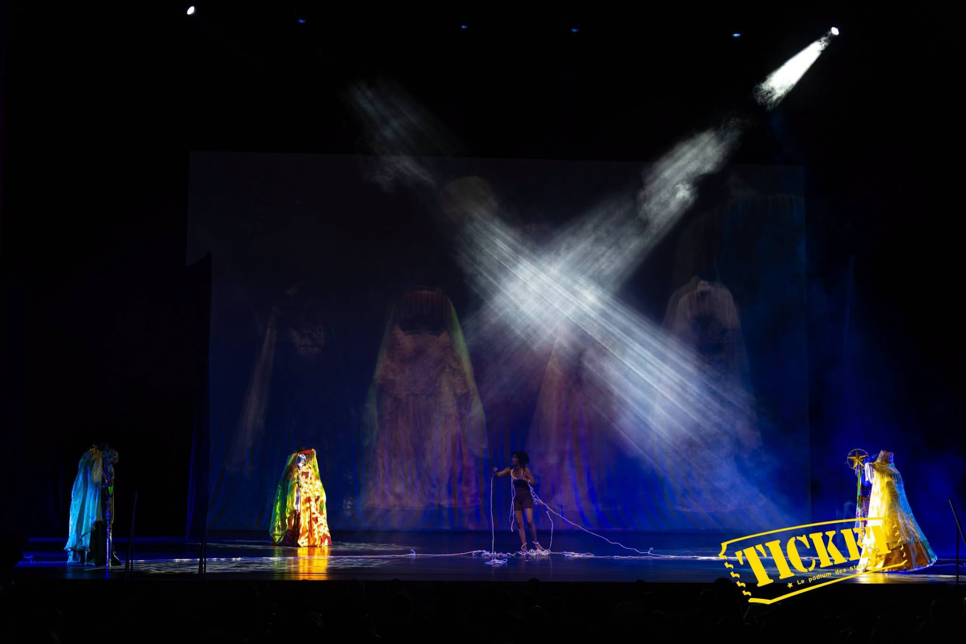 Wide stage view with a single spotlight cutting through mist