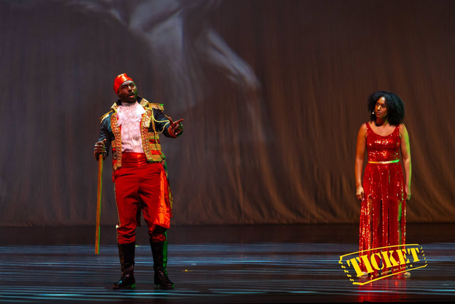 A performer in a red military coat with a woman in a red sequined gown