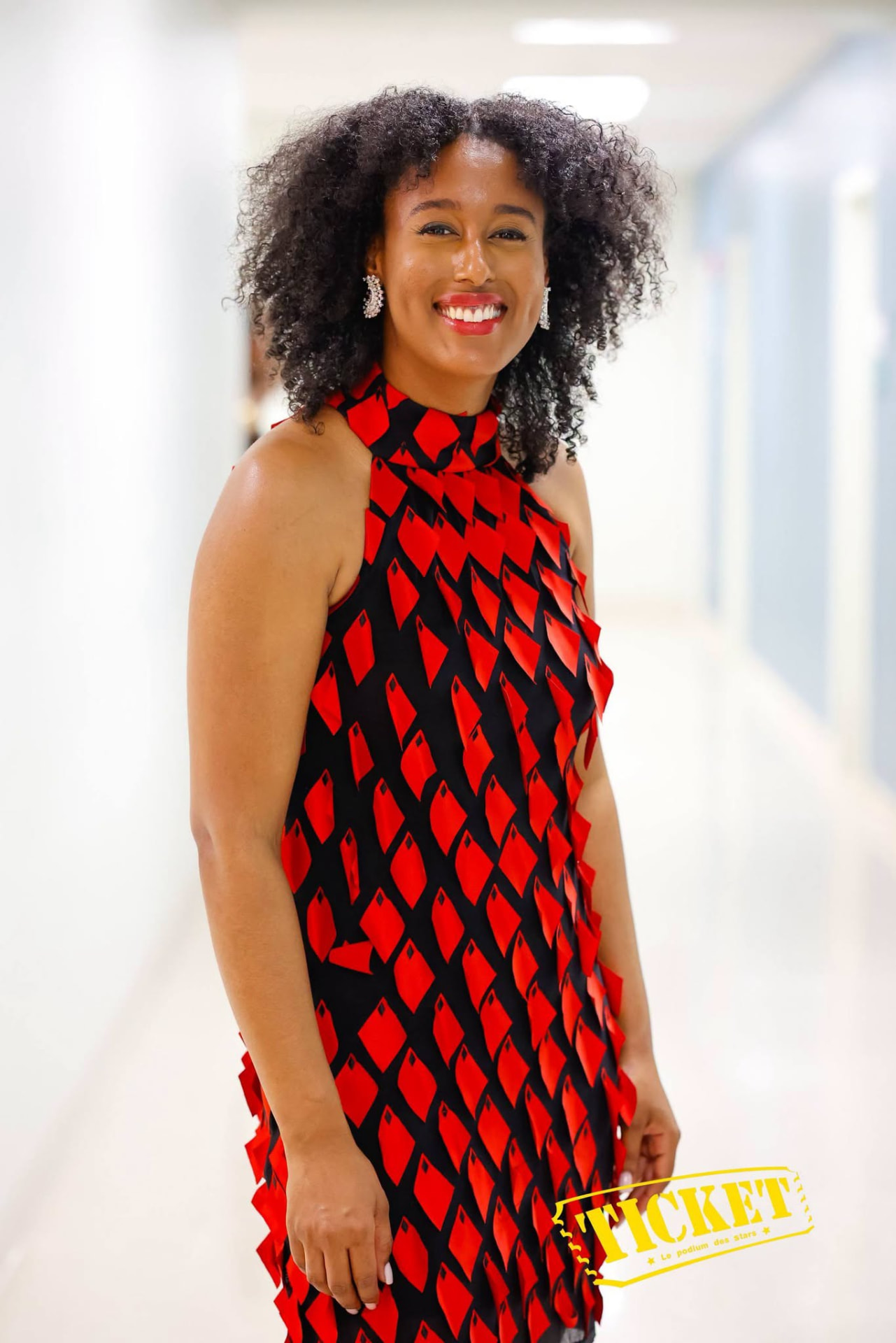 A guest in a red and black diamond-print dress backstage