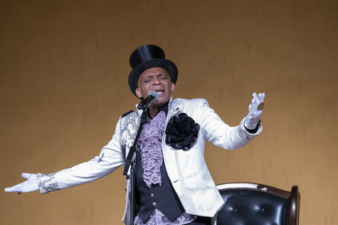 Erol Josué performing in a top hat and white embroidered jacket